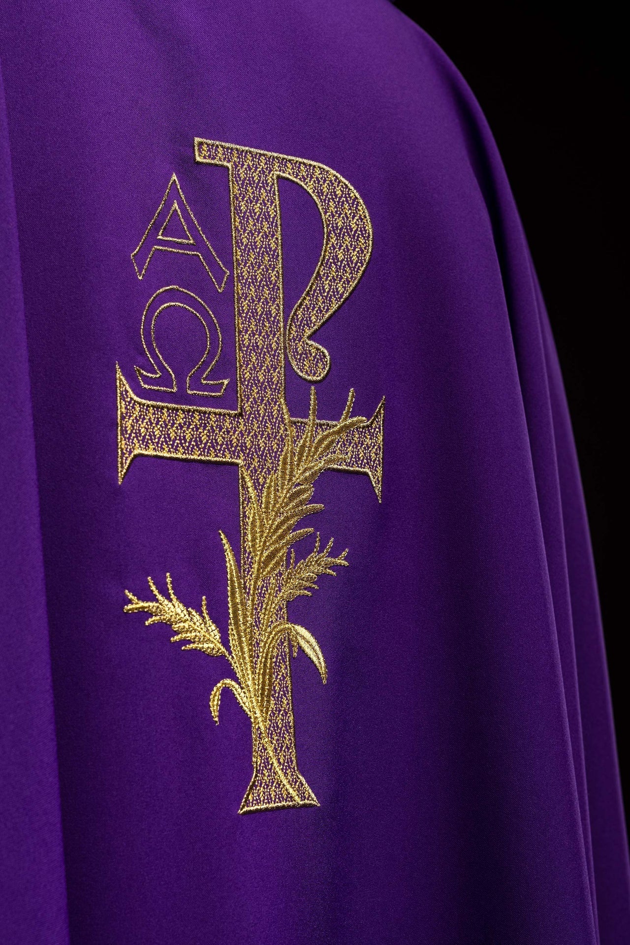 Casulla bordada con el símbolo Alfa y Omega y cuello ancho en color morado
