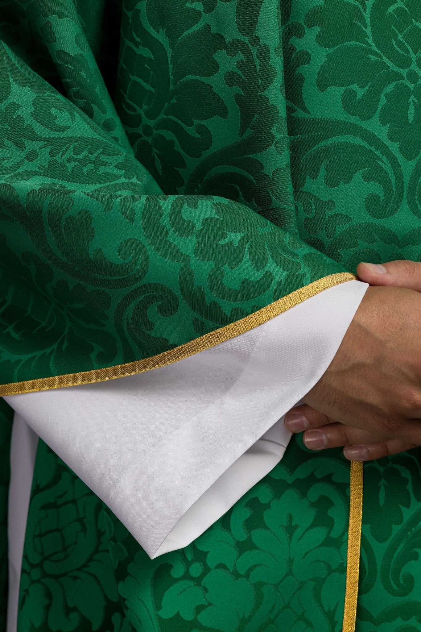 Casulla verde con motivo IHS y cuello ricamente bordado sobre tela decorativa
