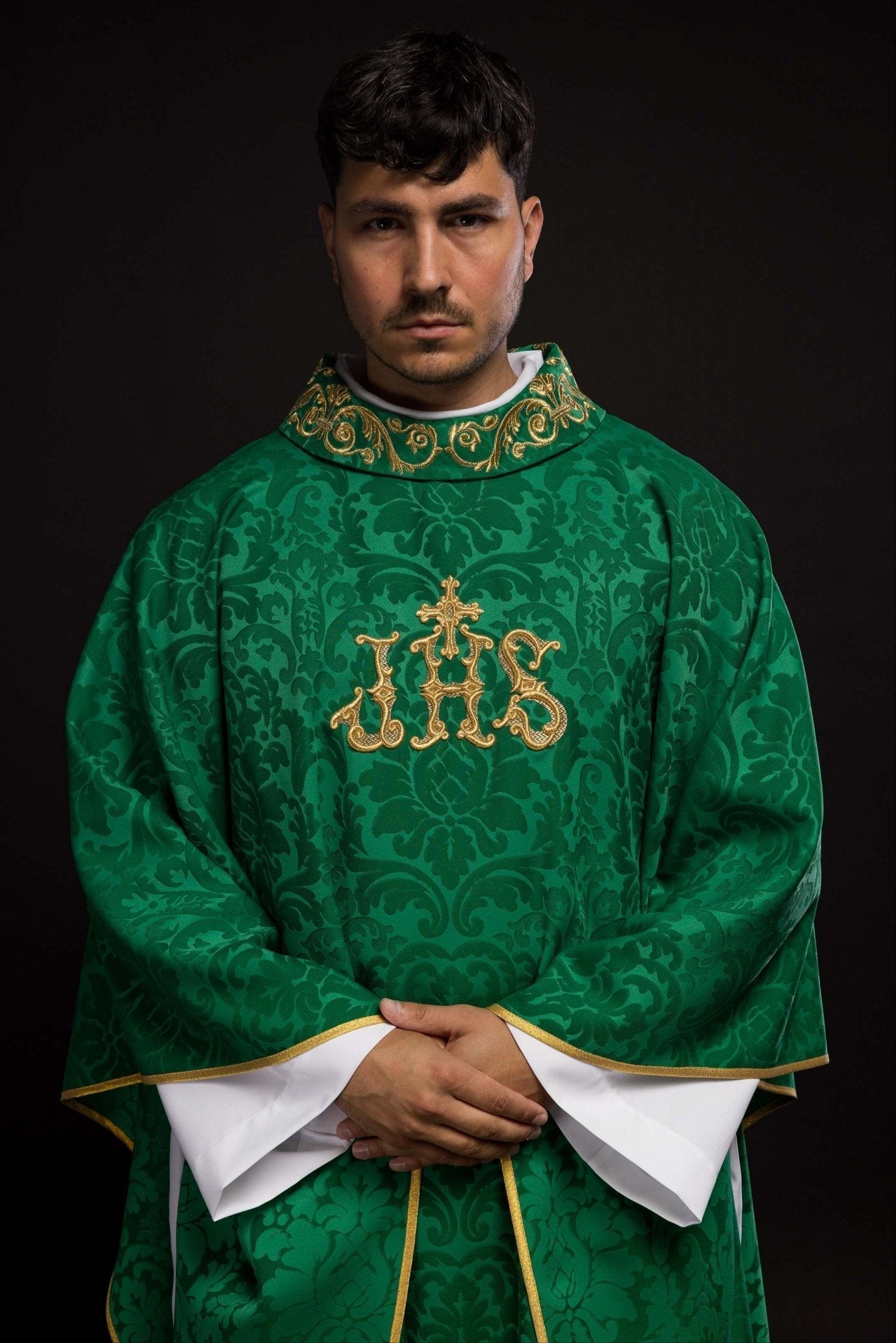 Casulla verde con motivo IHS y cuello ricamente bordado sobre tela decorativa
