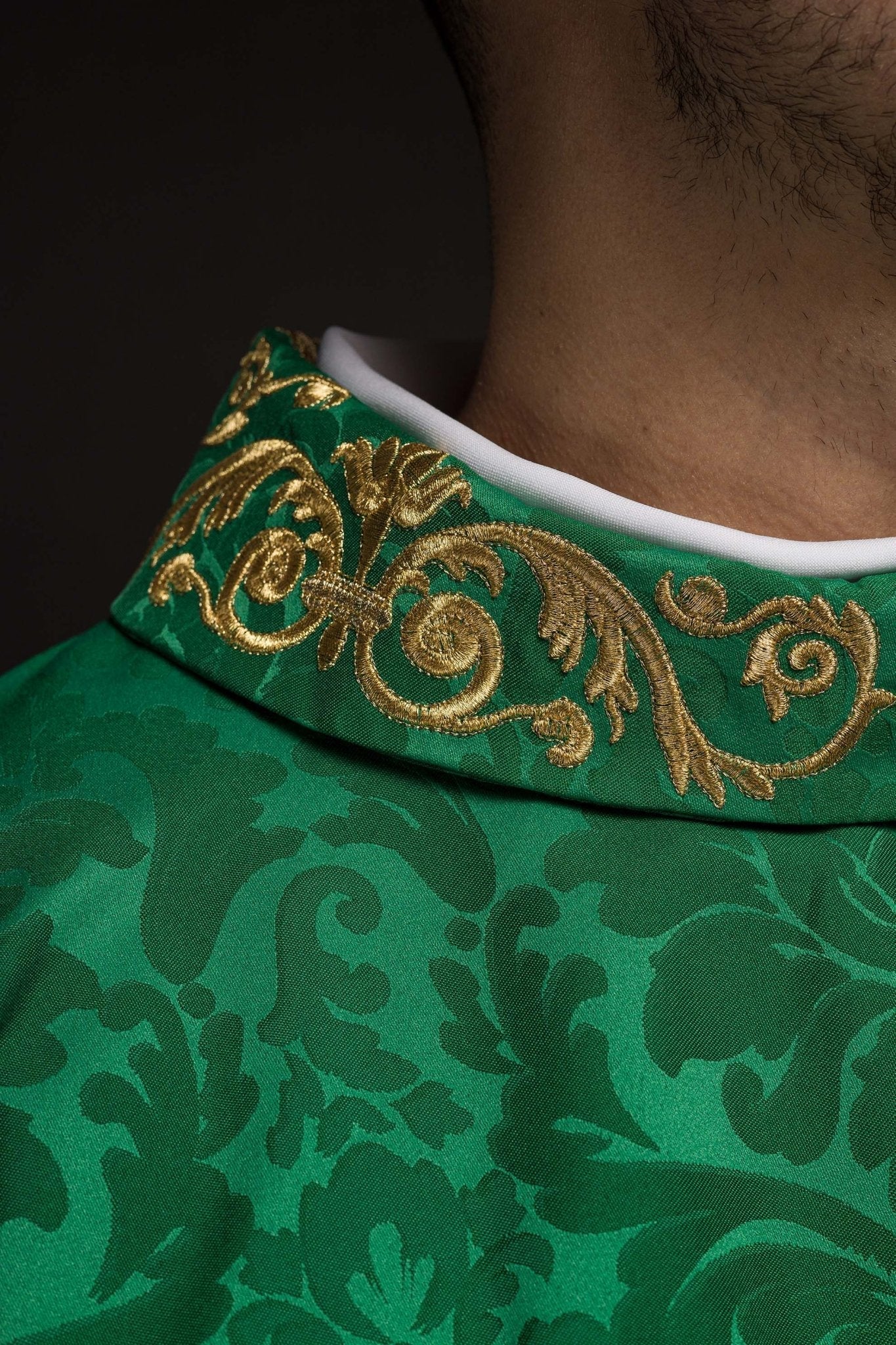 Casulla verde con motivo IHS y cuello ricamente bordado sobre tela decorativa
