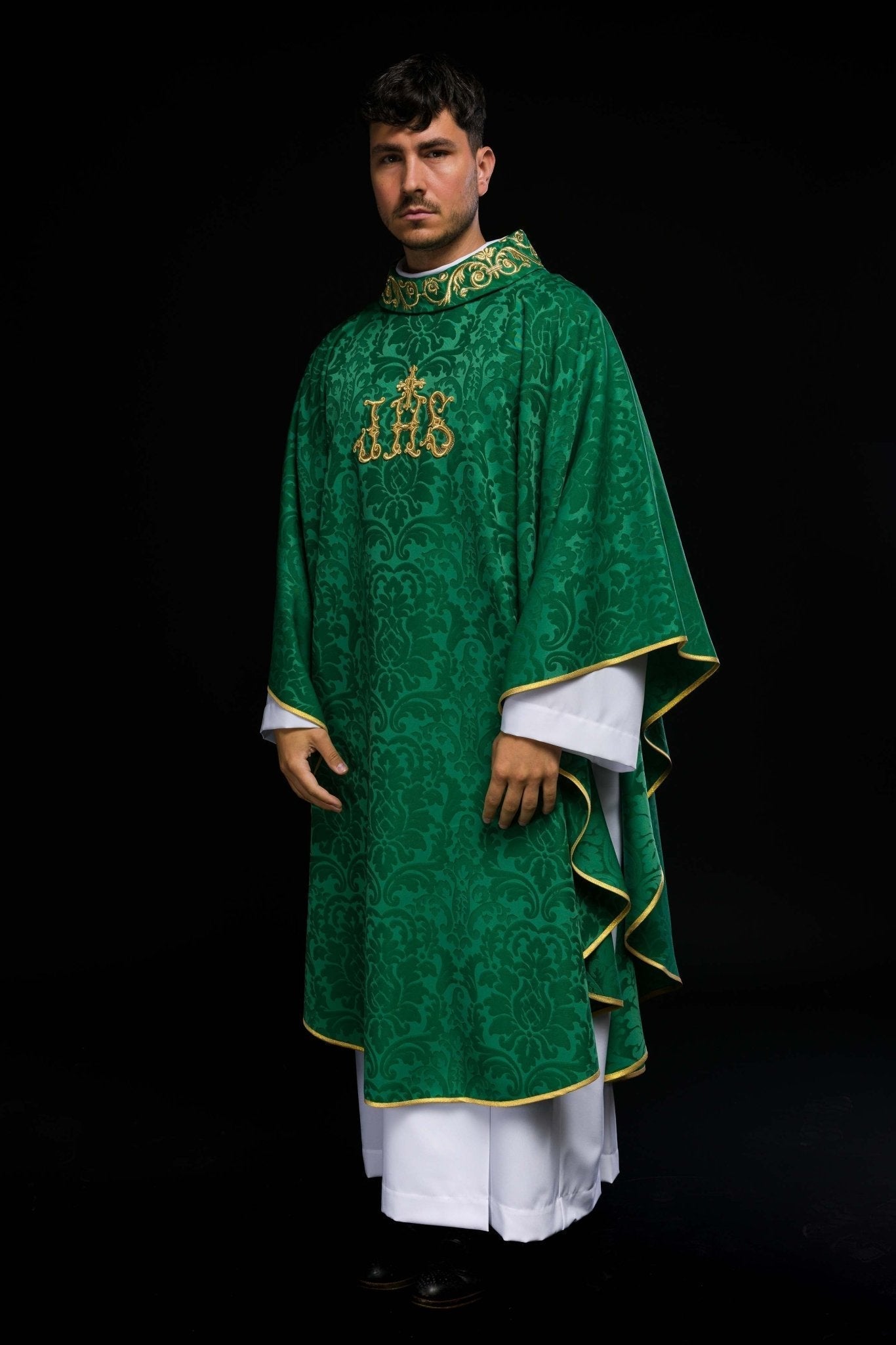 Casulla verde con motivo IHS y cuello ricamente bordado sobre tela decorativa