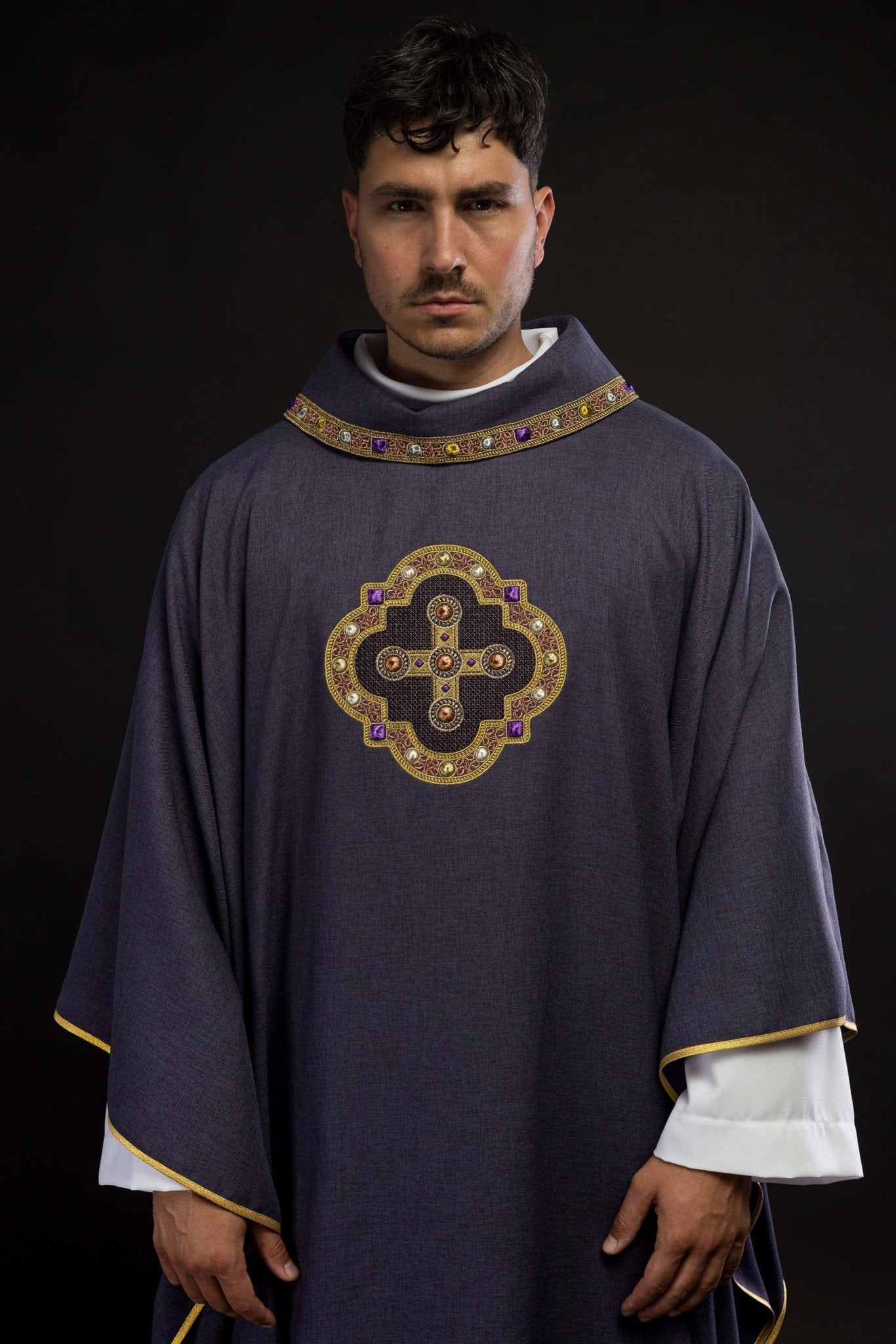 Casulla de color morado con ribetes bordados en el cuello y alrededor del bordado de la cruz.