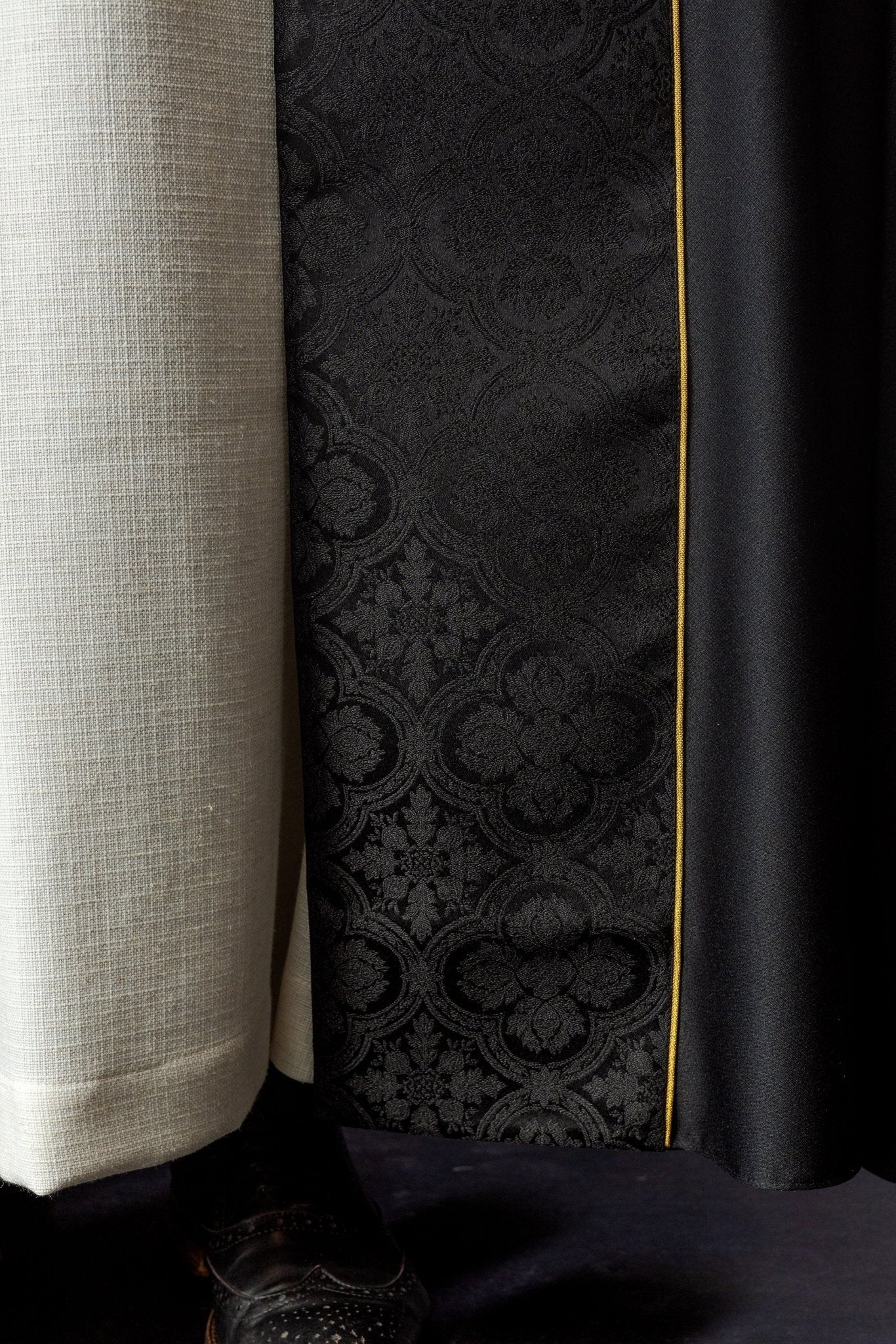 Capa pluvial negra con cruz dorada bordada en jacquard
