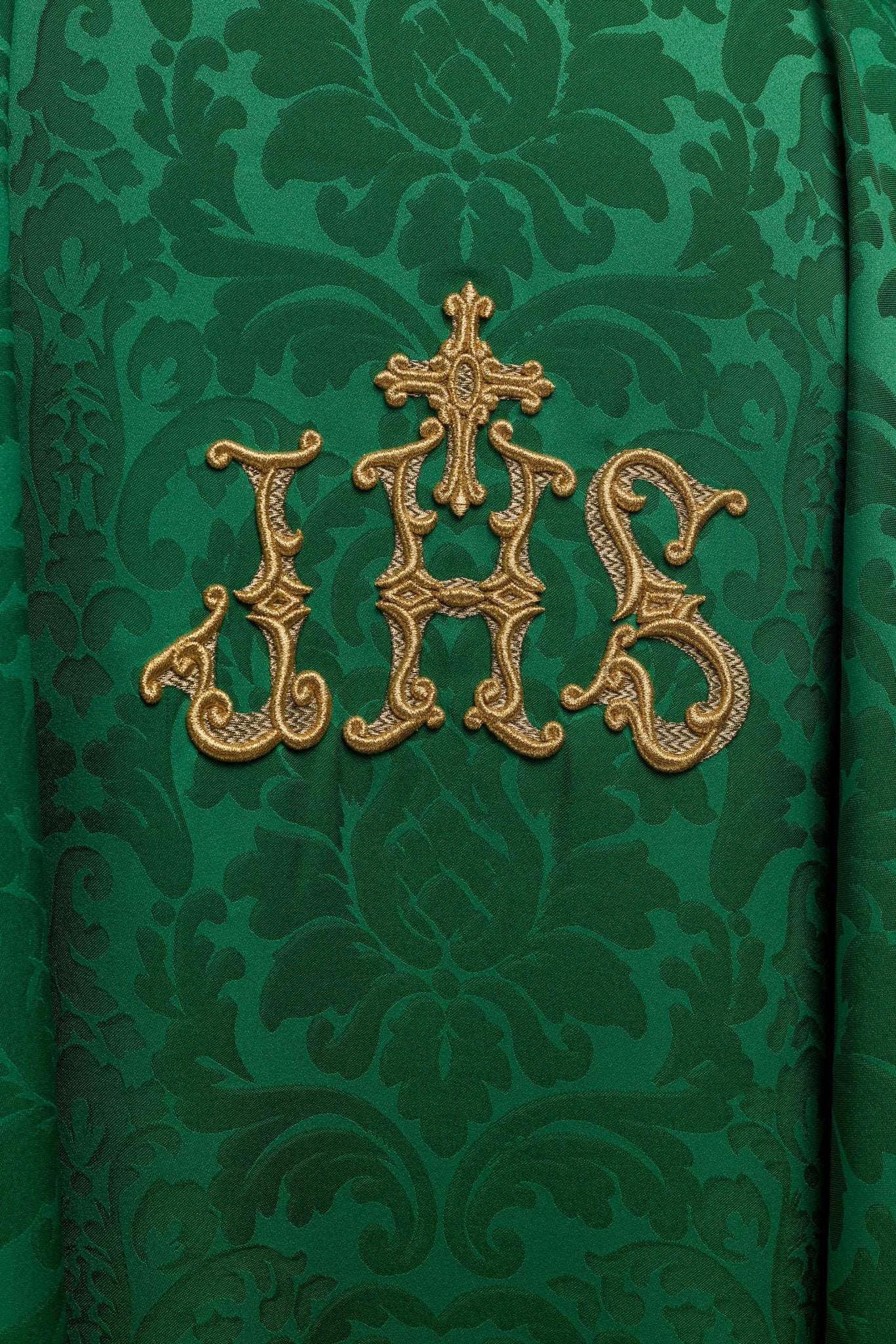 Casulla verde con motivo IHS y cuello ricamente bordado sobre tela decorativa