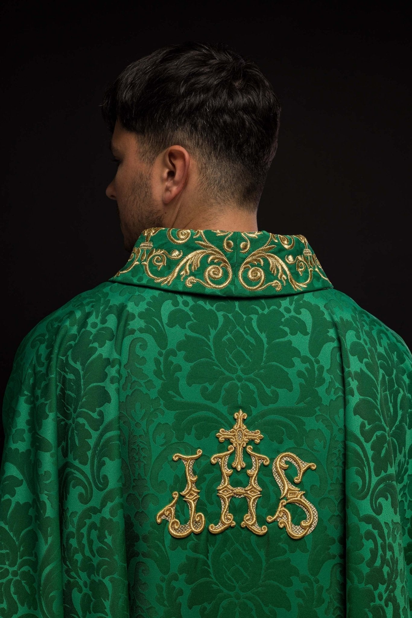 Casulla verde con motivo IHS y cuello ricamente bordado sobre tela decorativa