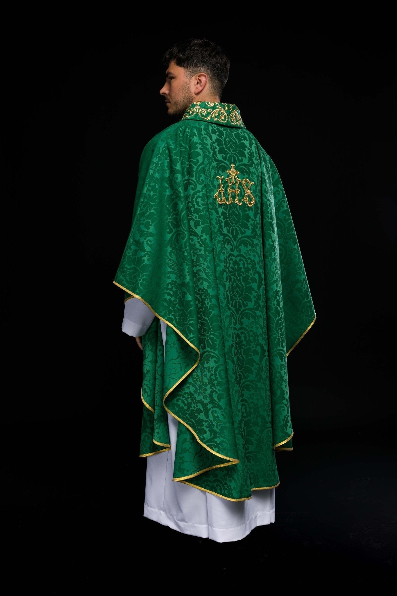 Casulla verde con motivo IHS y cuello ricamente bordado sobre tela decorativa