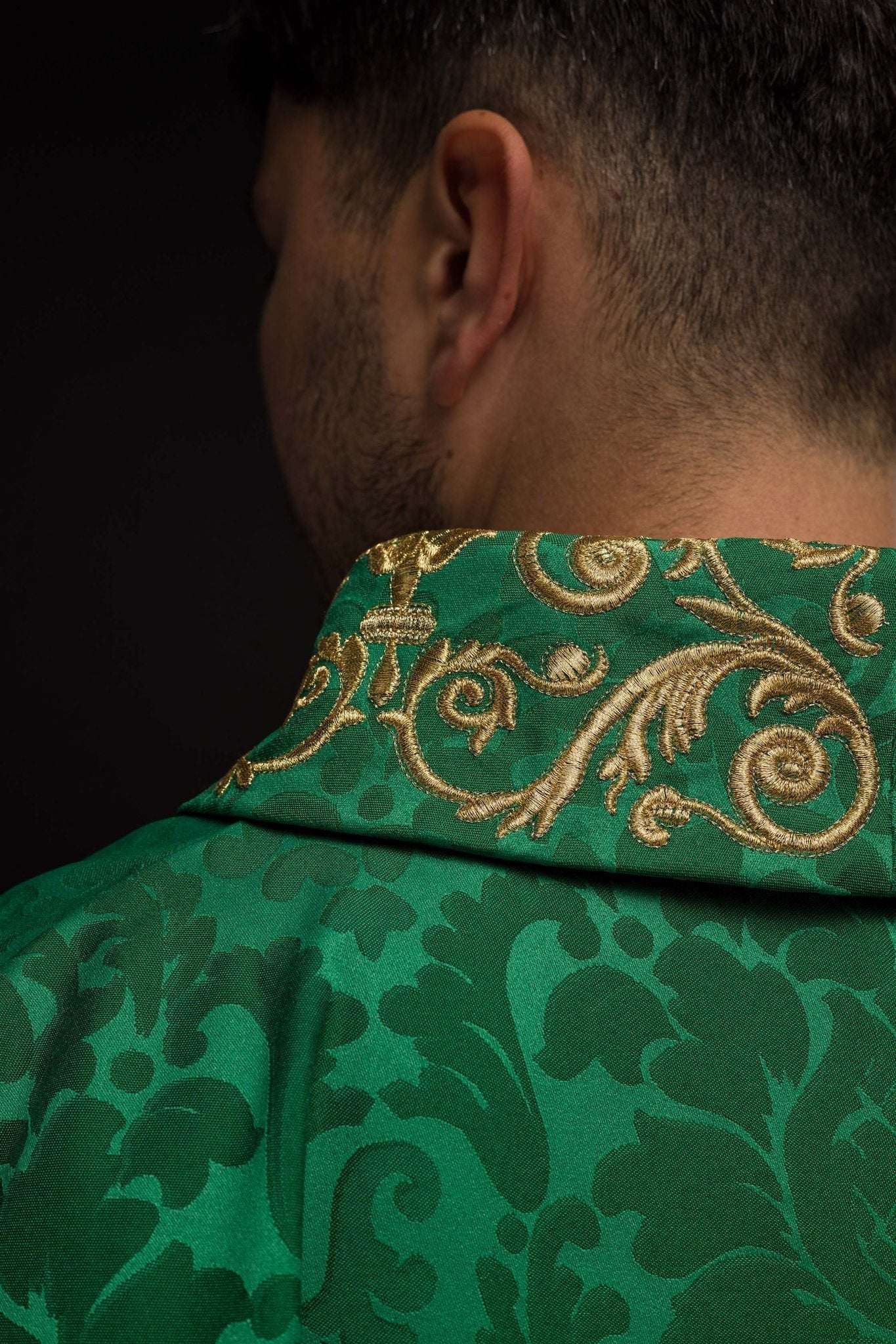 Casulla verde con motivo IHS y cuello ricamente bordado sobre tela decorativa