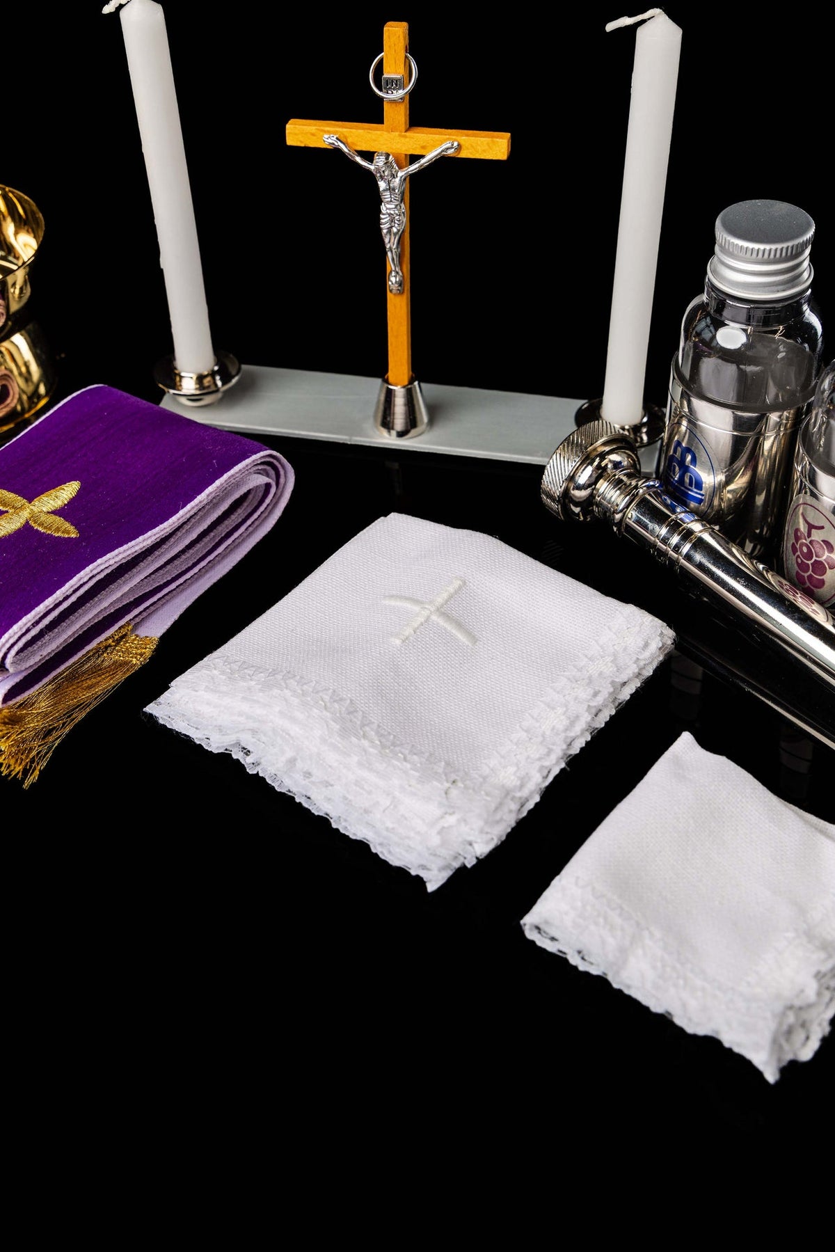 Accesorios de la maleta litúrgica con crucifijo, velas, frascos y paños blancos
