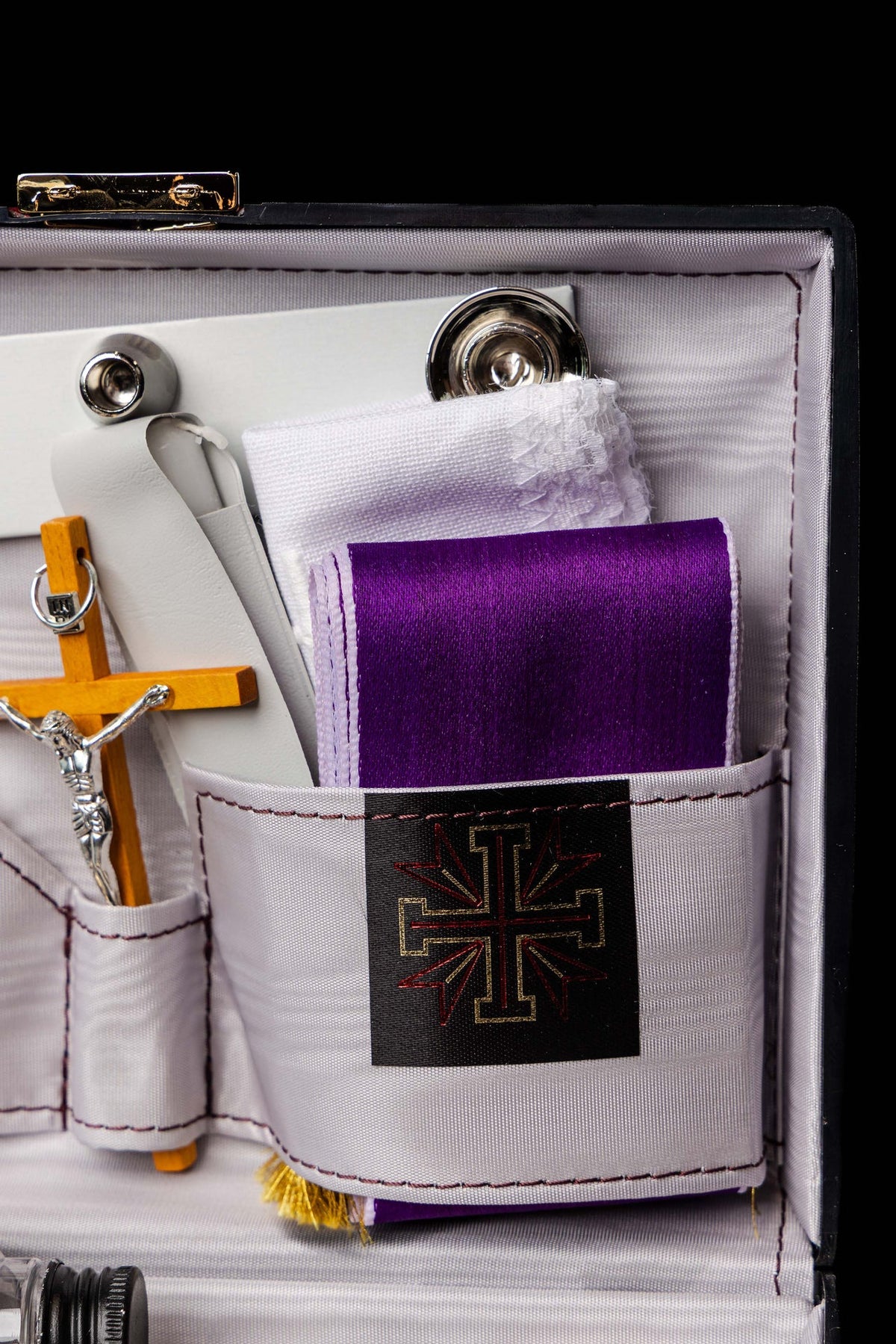 Detalle de maleta litúrgica con paño morado y bordado de cruz dorada
