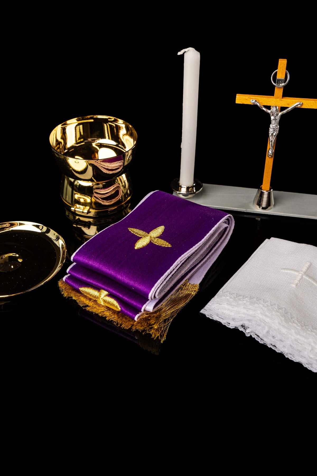 Accesorios de la maleta litúrgica: cáliz, vela, crucifijo y paño morado