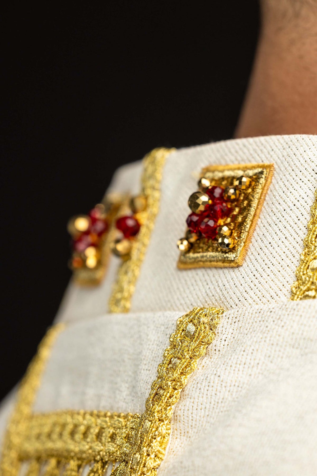 Casulla hecha a mano con piedras naturales, detalle de piedras rojas y galón dorado