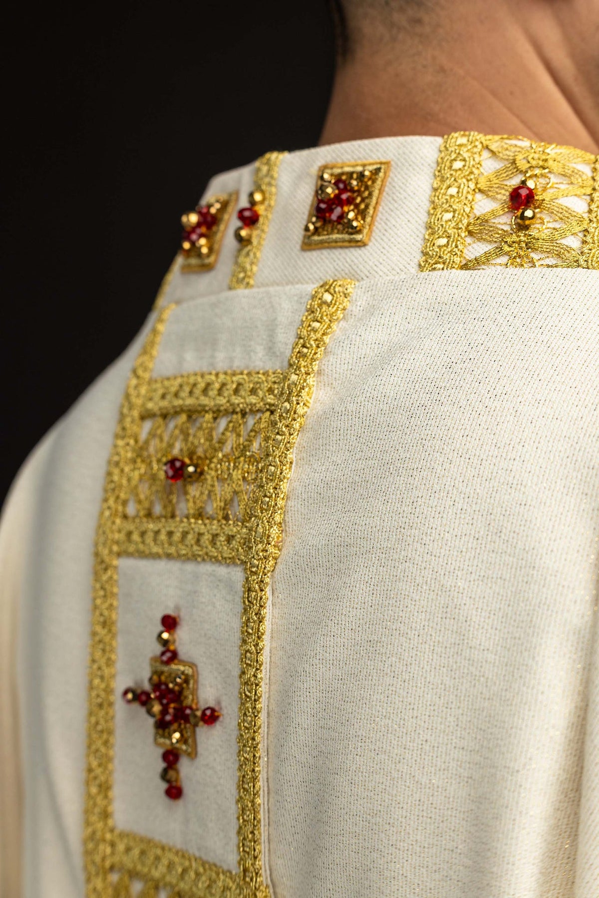 Casulla hecha a mano con piedras naturales, detalle lateral de bordado dorado y piedras rojas